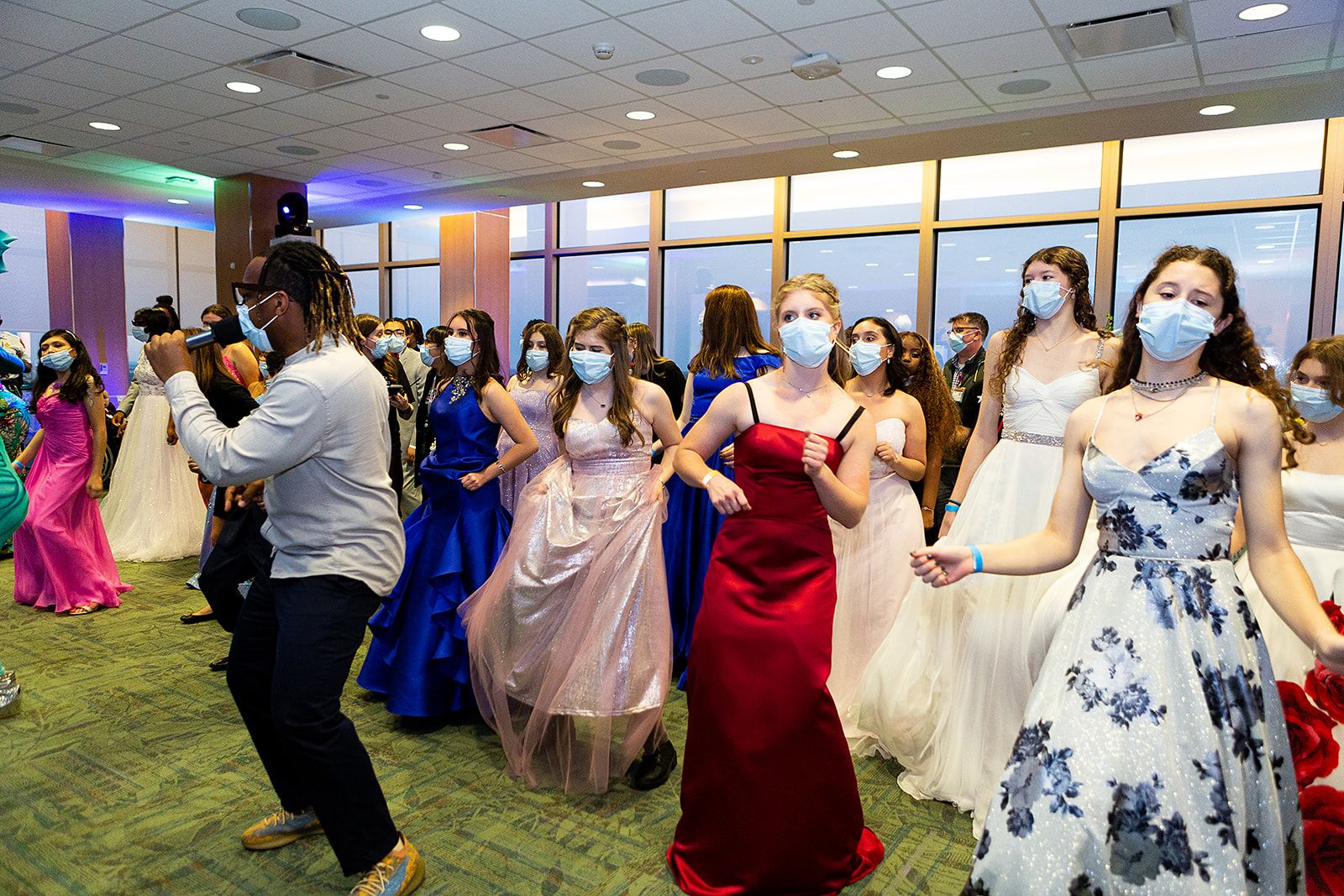 A large group of people in various colored prom dresses dancing in lines.
