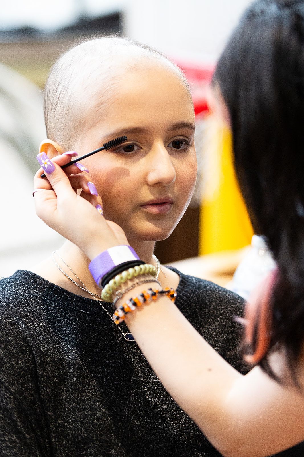 A prom attendee having mascara applied by someone else.