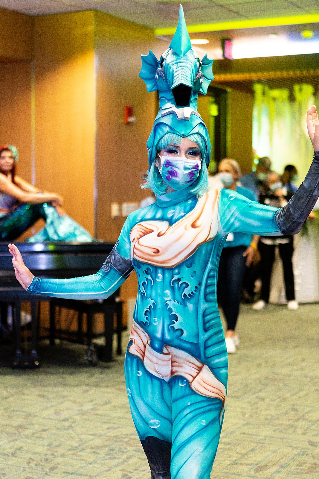 A performer dresses in an aqua blue and purple costume with a seahorse headpiece on.