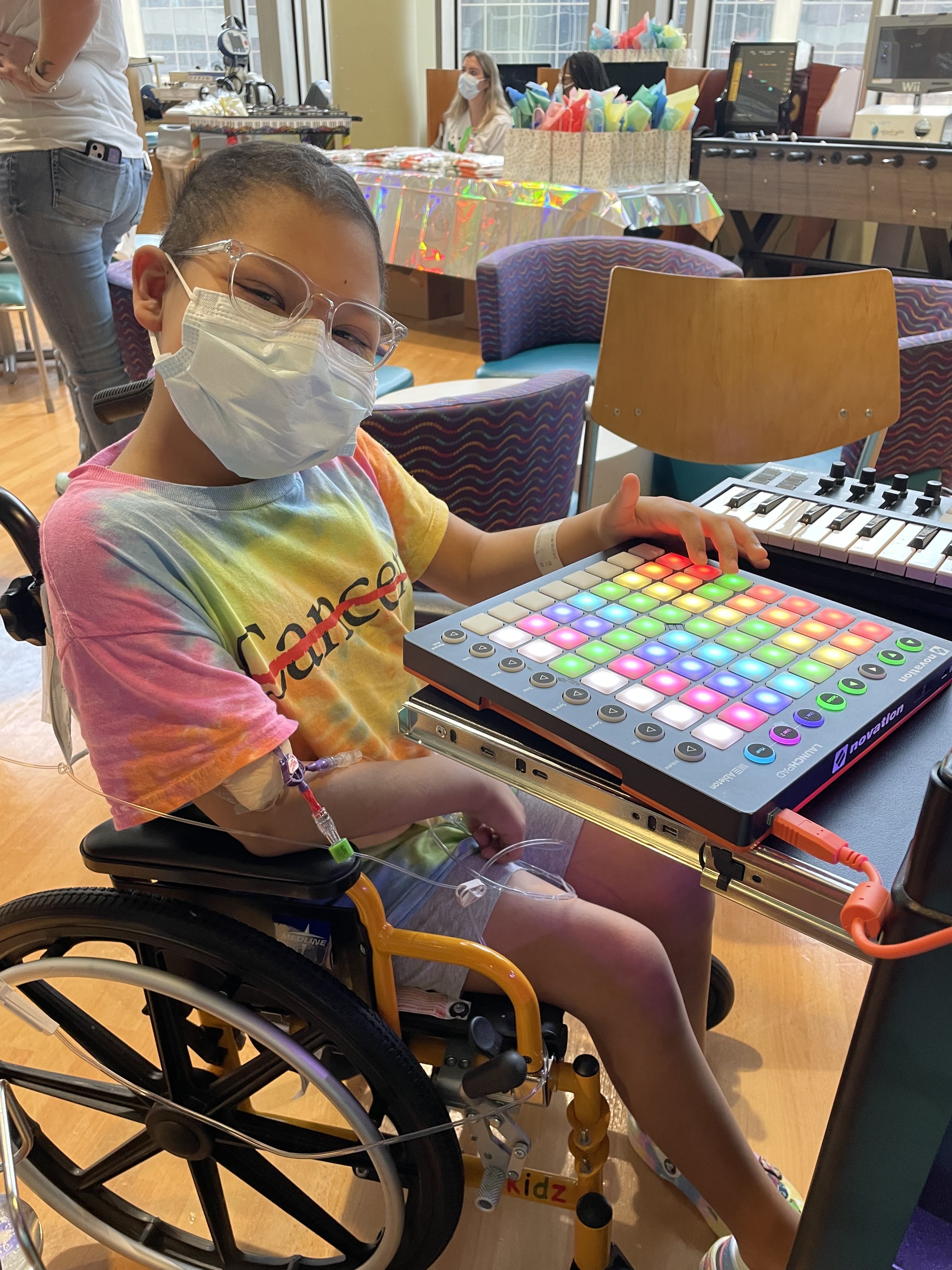 A child in a tie dye MD Anderson Cancer Center Strikethrough logo t-shirt pushing buttons on a soundboard.