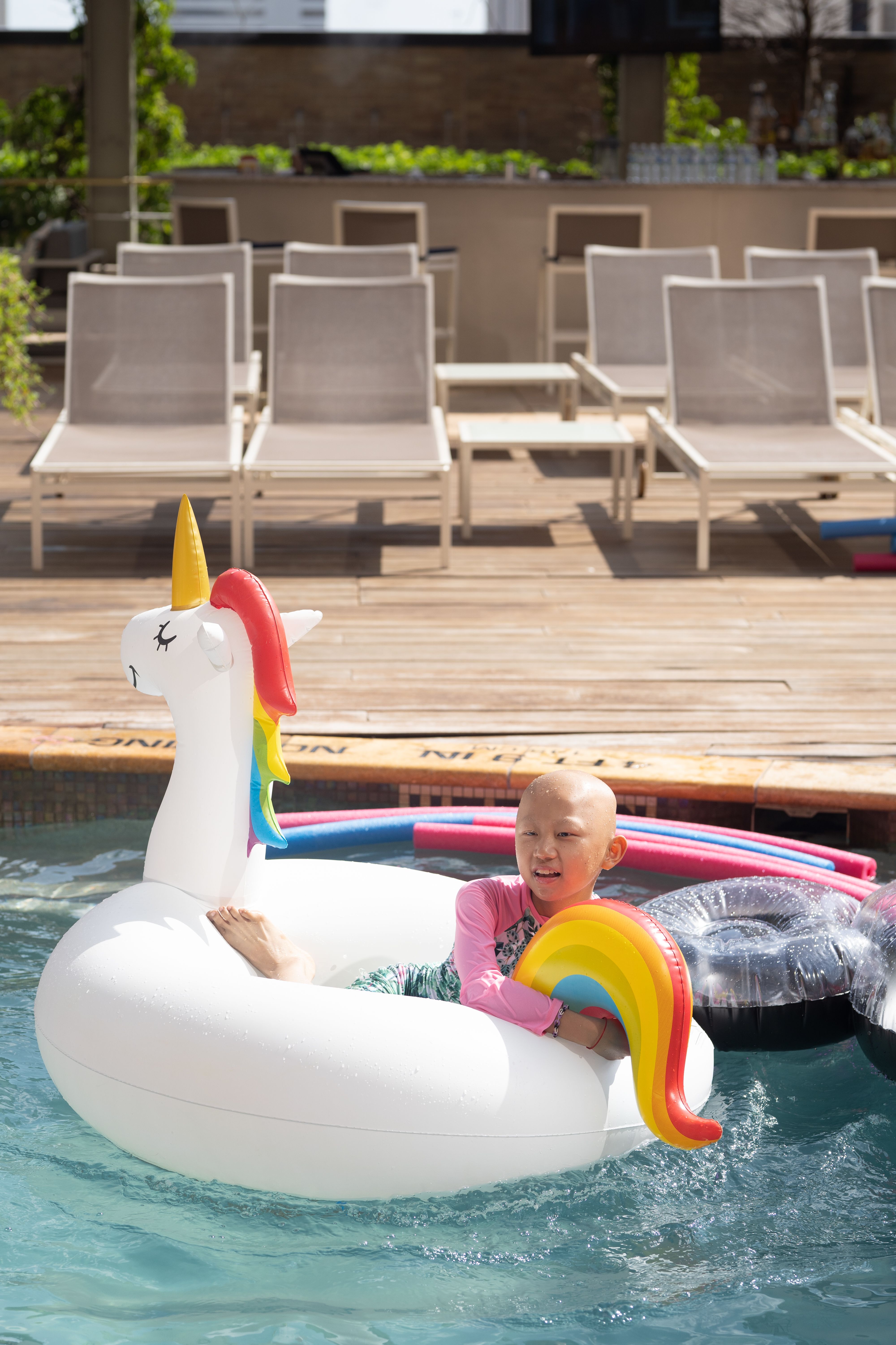 A child laying on an inflatable unicorn float in a swimming pool.