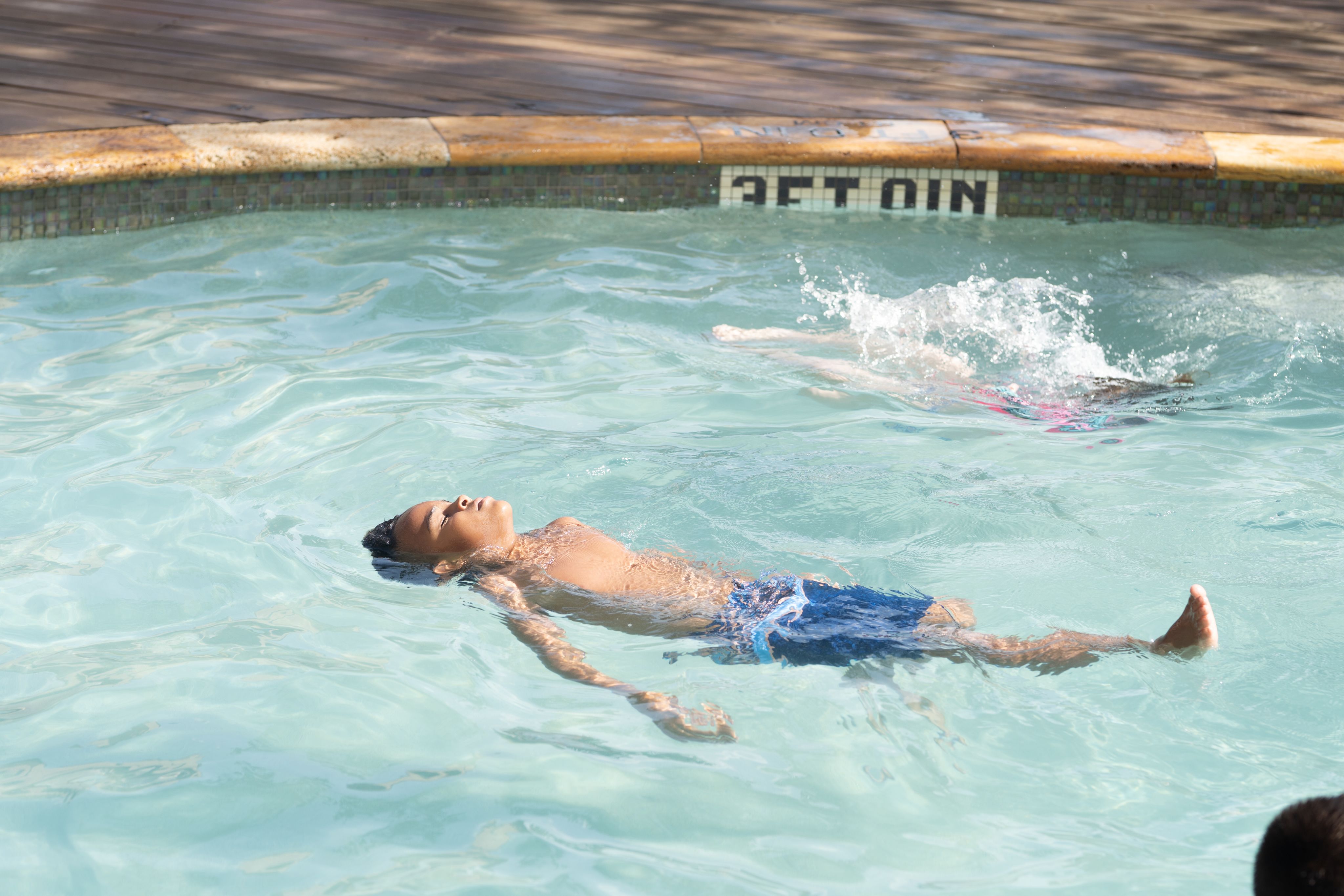 A child floating on his back in a swimming pool.