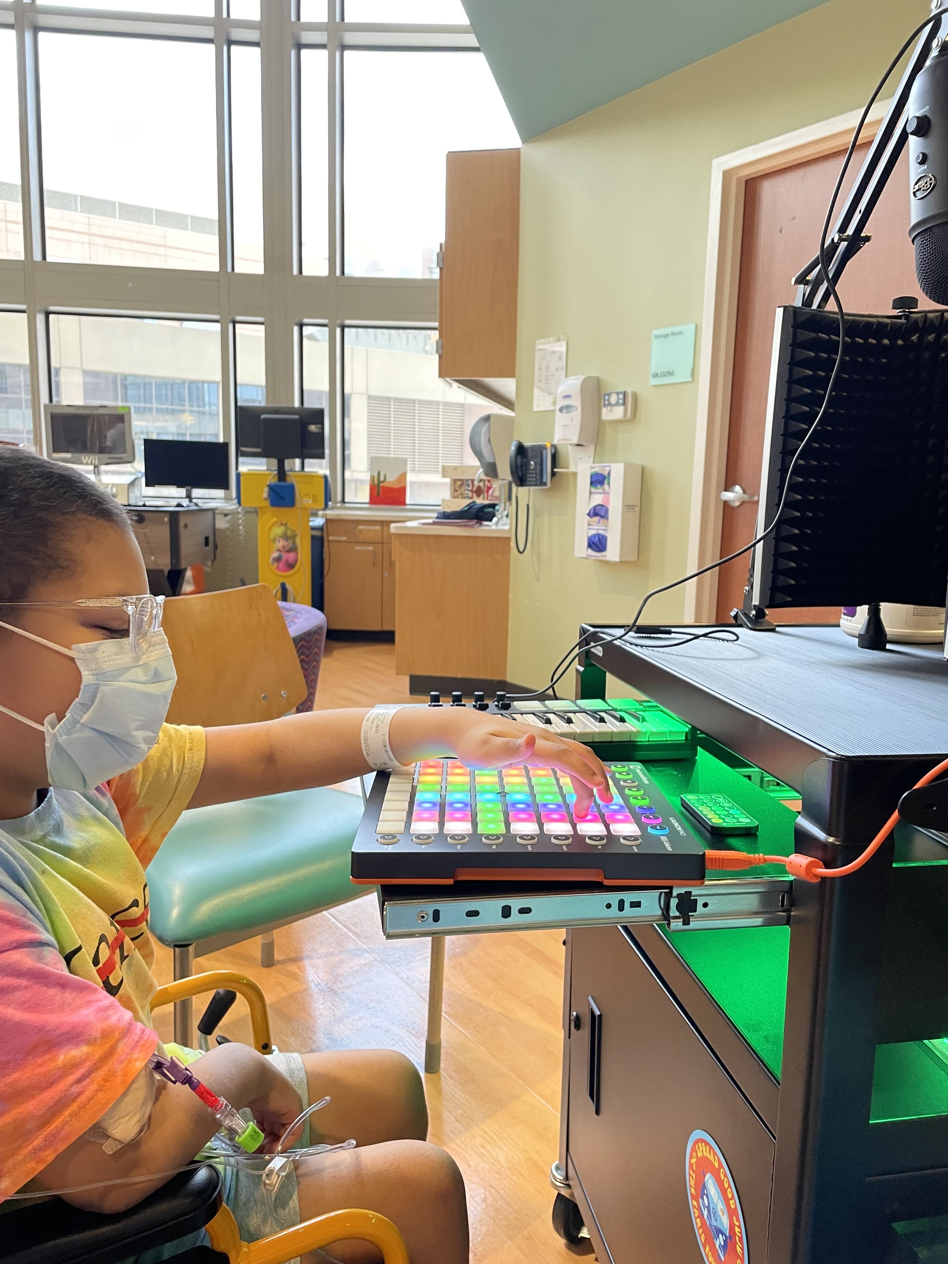A child in a tie dye MD Anderson Cancer Center Strikethrough logo t-shirt pushing buttons on a soundboard.