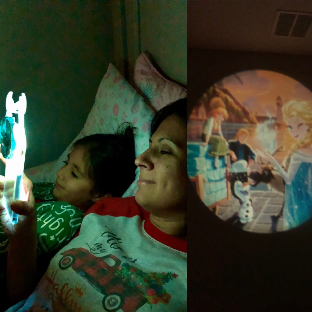 A woman and a child laying down watching a movie on a projector.