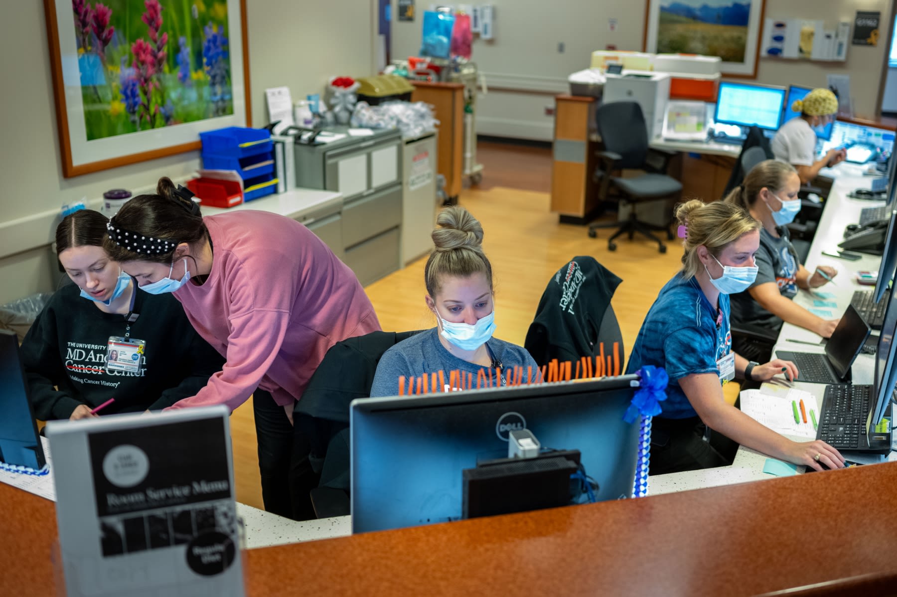 Several people working behind computers while wearing surgical face masks.