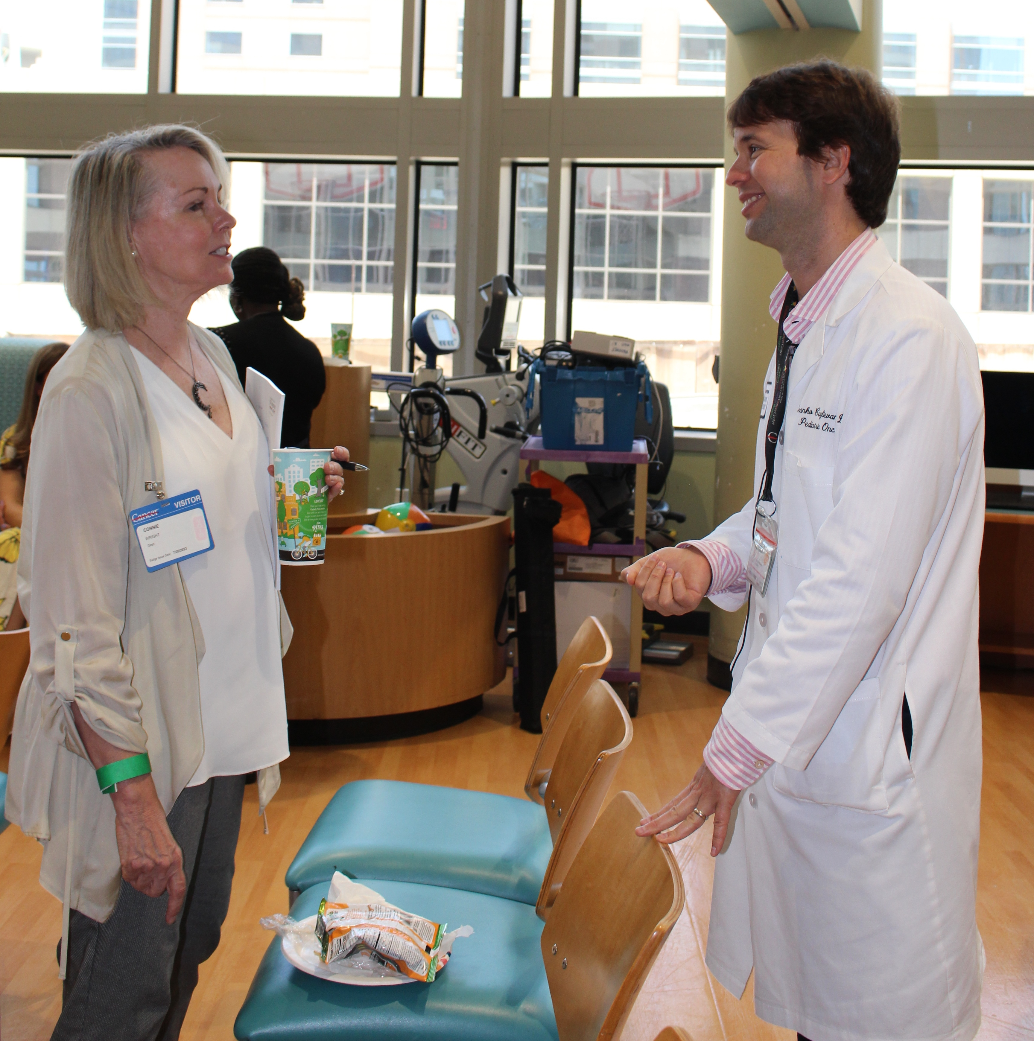 Connie Wright holding a cup while speaking to Dr. Branko Cuglievan.