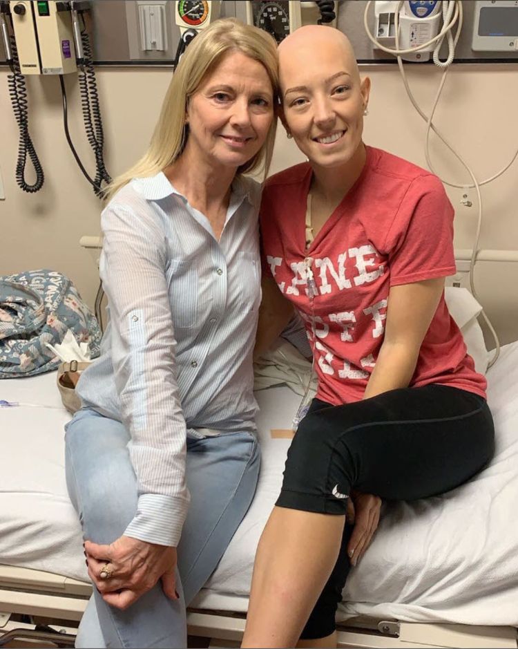 A blonde woman sitting next to Kate on a hospital bed, smiling at the camera. 